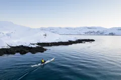 Kayaking beside a snowy Arctic shoreline