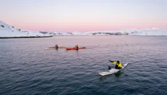 The expedition team paddling beneath a pink sky