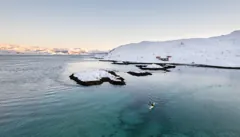 Kayaking past snow-covered islands and cabins