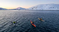 The three kayakers crossing the fjord at sunset
