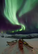 Northern lights above the kayaks on the snow