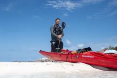 Gary standing beside the kayaks on the beach