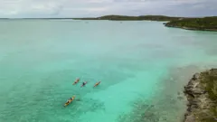 The team kayaking across a turquoise bay