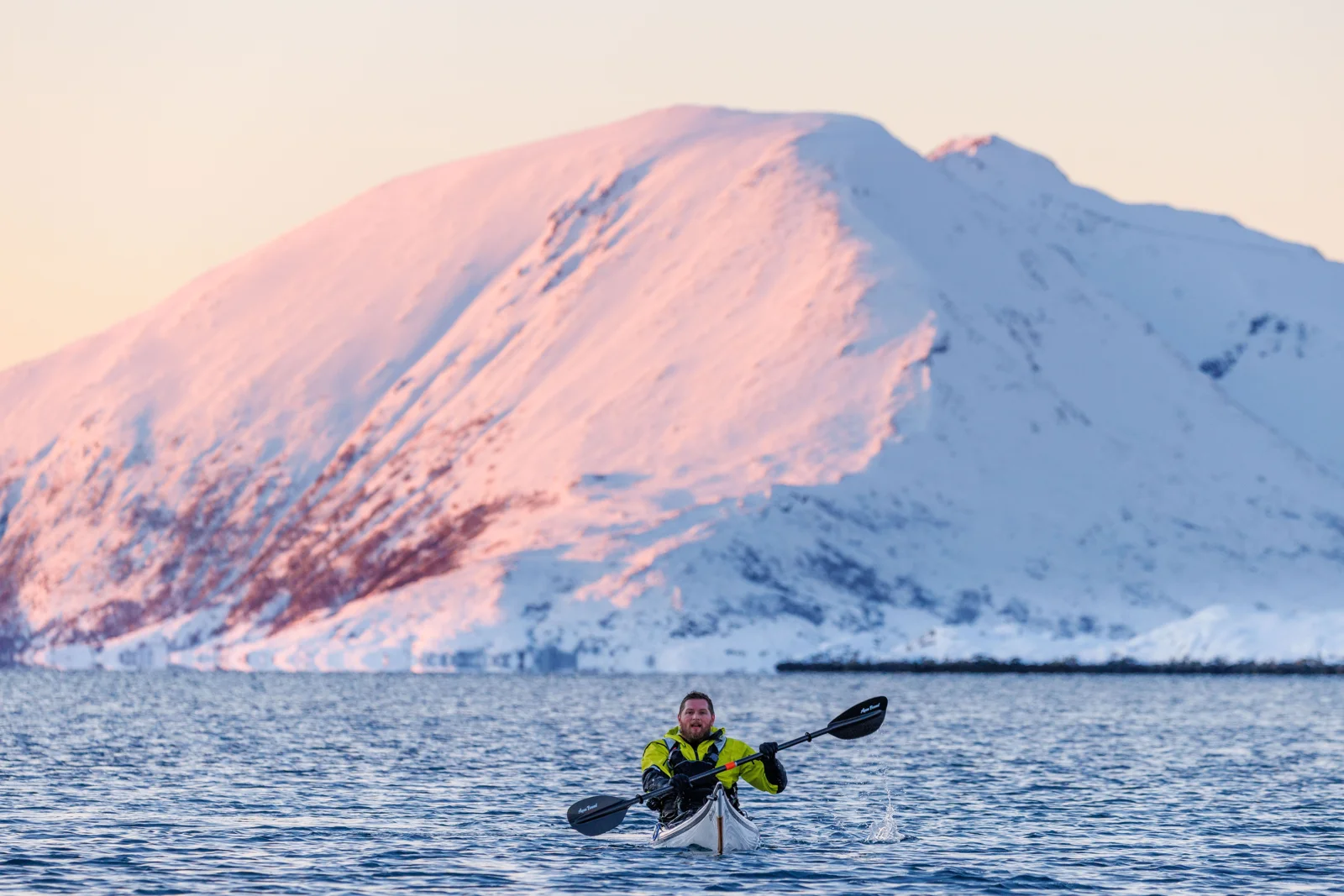 Kayaking beneath a snow-covered Arctic mountain